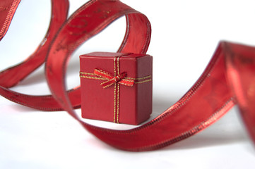 Red gift with bright red decorative ribbon, isolated on white background.