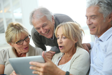 Group of retired people sitting in sofa and using tablet