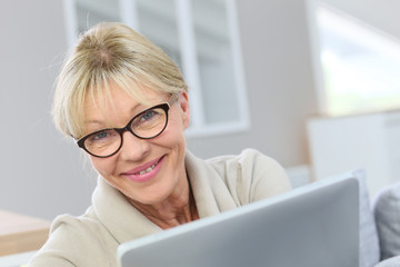 Senior woman with eyeglasses using digital tablet at home