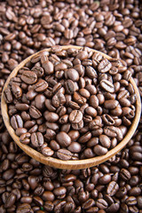 roasted coffee beans in wooden bowl with coffee background