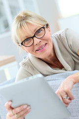 Senior woman with eyeglasses using digital tablet at home