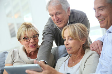 Group of retired people sitting in sofa and using tablet