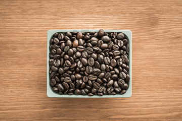 brown coffee beans in cup on wood background