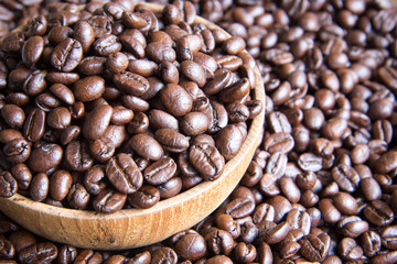 roasted coffee beans in wooden bowl with coffee background