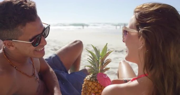 Multi racial Couple drinking pineapple cocktails on the beach