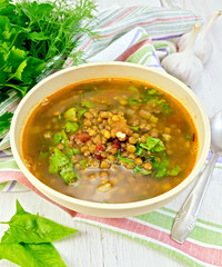 Soup lentil with spinach in bowl on light board