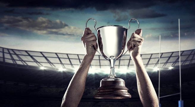 Composite image of successful rugby player holding trophy