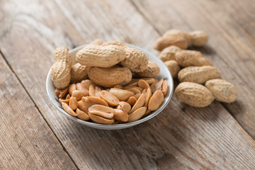 Peanut or arachis in white bowl on wood table.