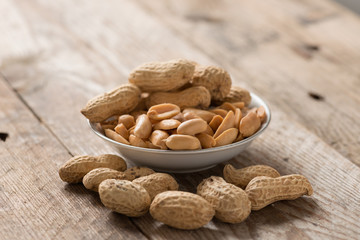 Peanut or arachis in white bowl on wood table.