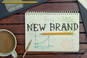 work place with notebook with note about: New Brand with laptop