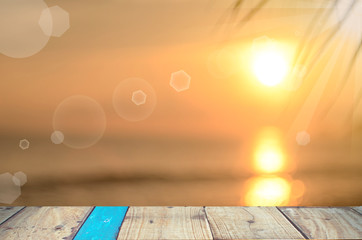 Fototapeta na wymiar Blur tropical sunset beach on empty old table wood background.
