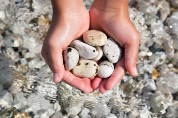 Sassi raccolti nelle mani di una bambina al mare