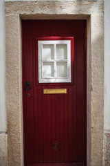 red door with white window with a gold mailbox