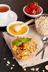 cereal flakes with fresh berries in a bowl, cup of tea and honey