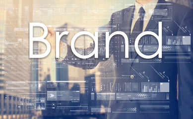 businessman writes on board text: Brand - with sunset over the c