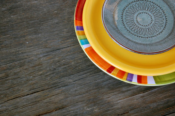 Colorful plates on wooden background