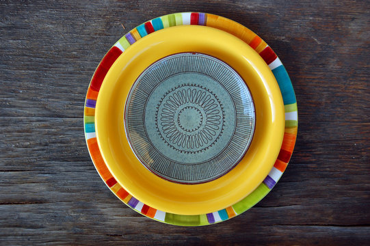 Colorful plates on wooden background