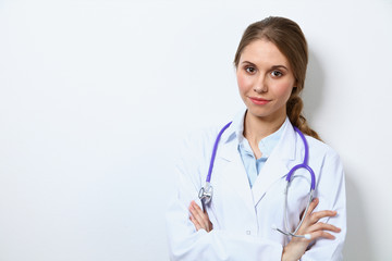 Friendly smiling young female doctor, standing near wall