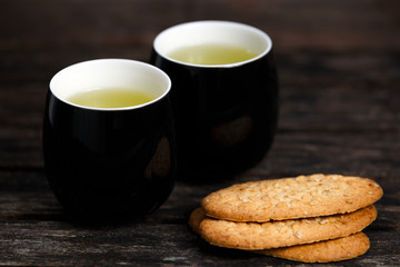 Mugs of Green Tea and rustic cookies with nuts. on old wooden table