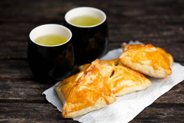 Homemade pastry with beef, potato and onion. with Mugs of  Green Tea on old wooden table.