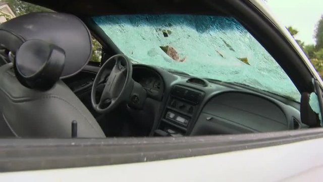 A man destroys his car with a sledgehammer.