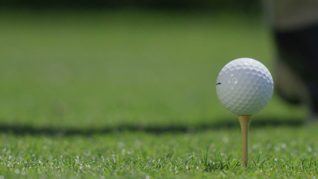 Close-up of a golf ball being hit off a tee.