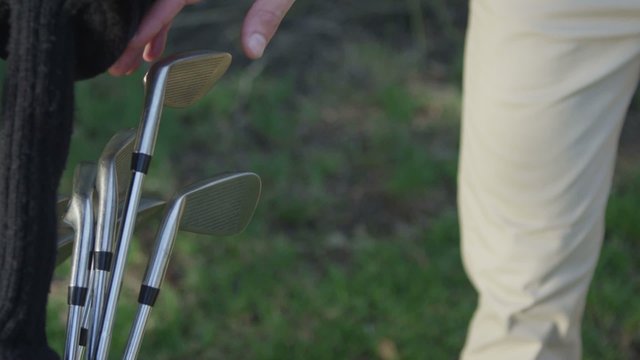 Close-up of a golfer pulling a club from his bag.