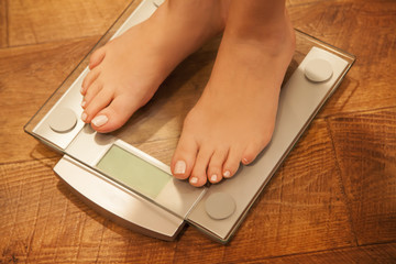 Woman's feet standing on weight scale.
