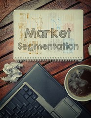 Notebook with text inside Market Segmentation on table with coff