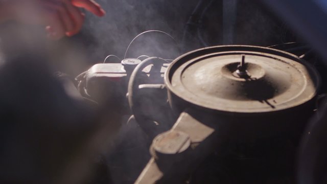 Close-up of an old Chevy pickup truck engine as it steams and fingers point to problem parts.