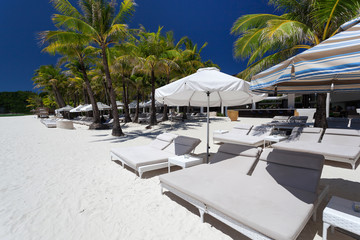 Sun umbrellas and beach beds on tropical coastline