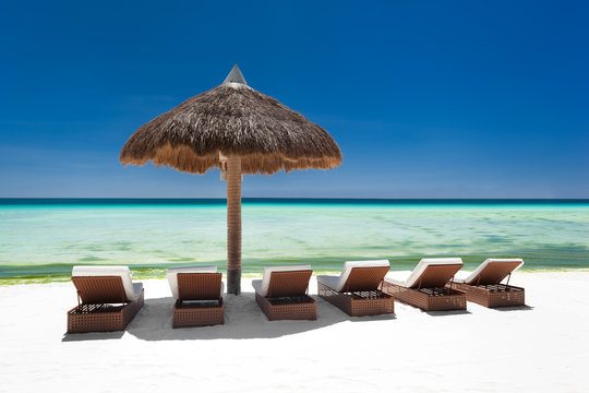 Sun umbrella and beach beds on tropical coastline