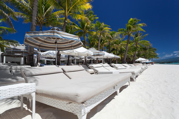 Sun umbrellas and beach beds on tropical coastline