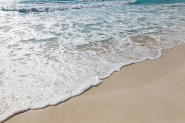 Sea waves with foam on white sandy beach