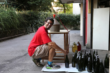 young man smiling while bottling the wine at home