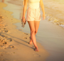 Beach travel - woman walking on sand beach leaving footprints in