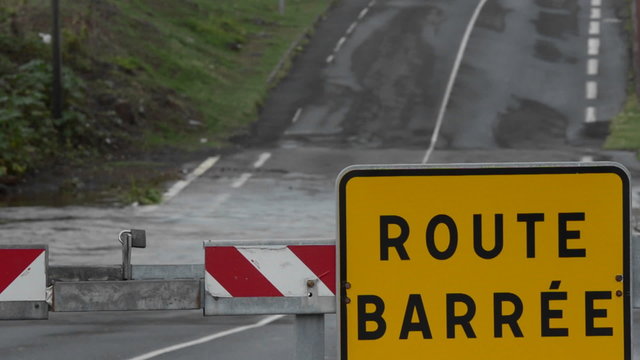 A road sign in French indicates that the road is closed during a big storm.