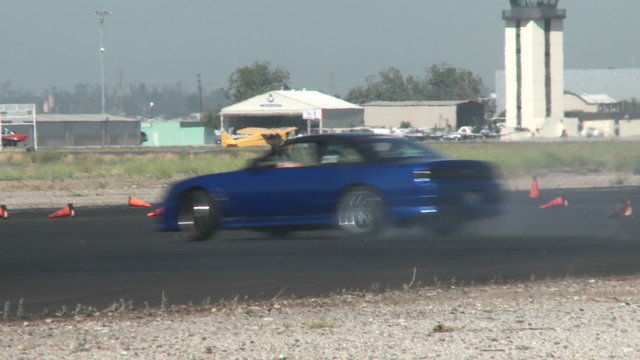 A blue car slides through a drifting course at Camarillo Airport in Camarillo California.