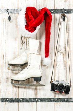 Red Santas hat, retro photo camera and white ice skates