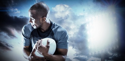 Composite image of rugby player looking away while catching ball
