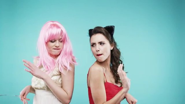 Girlfriends dancing wearing red dress and pink hair in slow motion party photo booth 