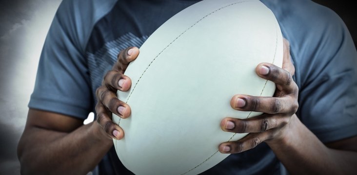 Composite image of mid section of sportsman holding rugby ball