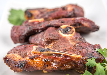 Roasted pieces of lamb on white plate over white background