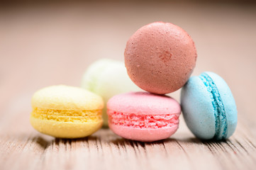A lot of french colorful macarons on a woody floor