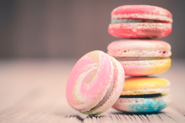 A lot of french colorful macarons on a woody floor in vintage to