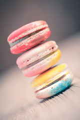 A lot of french colorful macarons on a woody floor in vintage to