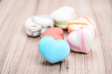 A lot of french colorful macarons in .heart shape on a woody flo