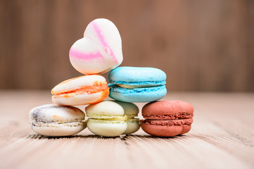 Fototapeta na wymiar A lot of french colorful macarons in .heart shape on a woody flo