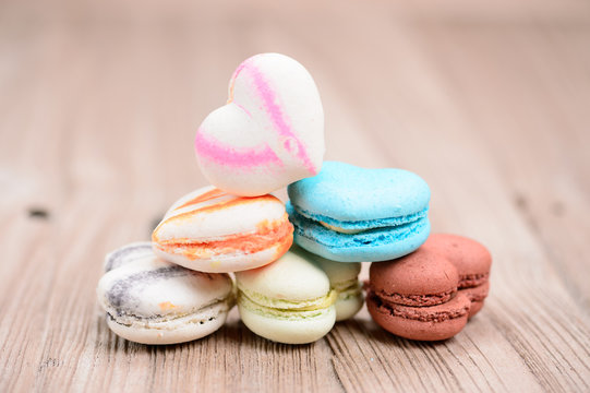 A lot of french colorful macarons in .heart shape on a woody flo