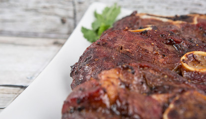 Malaysian dish of roasted lamb in a white plate over wooden background